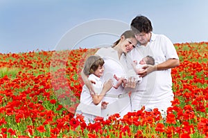 Young family with two children in a red flower field