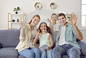 Young family with two children wave their hands in front of web camera to greet their relatives.