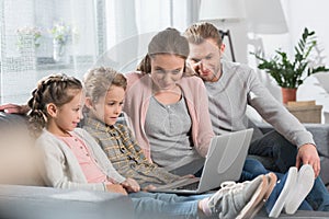 Young family with two kids sitting on couch in living room