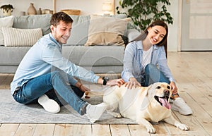 Young family of two people sitting on floor with dog