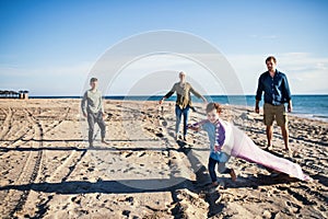 Young family with two small children walking outdoors on beach.