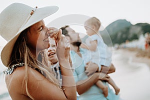 A young family with two toddler children having fun on beach on summer holiday.