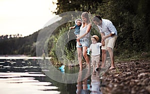 A young family with two toddler children outdoors by the river in summer.