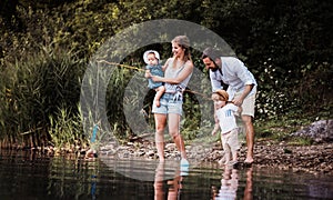 A young family with two toddler children outdoors by the river in summer.