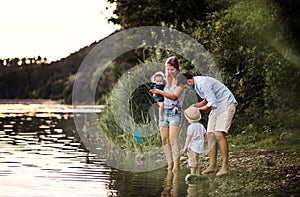 A young family with two toddler children outdoors by the river in summer.