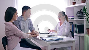 Young family visiting doctor, a physician consults a couple about fertility sitting at the desk in the medical office