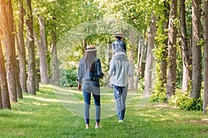 Young family walking in forest, father carrying his daughter on shoulders