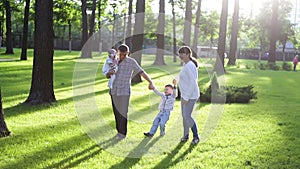 Young family walks in the summer park on the grass