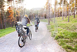 Young family in warm clothes cycling in autumn park