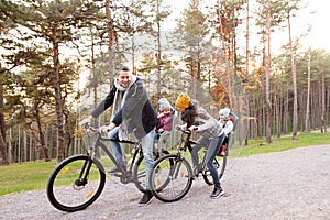 Young family in warm clothes cycling in autumn park