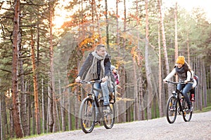 Young family in warm clothes cycling in autumn park