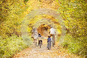 Young family in warm clothes cycling in autumn park