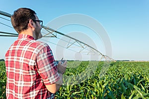 Young farmer or agronomist inspecting a corn field using a drone