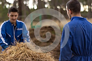 Young farmer couple collecting and cleaning straw from farm and barnyard. cleaning and animal care concept