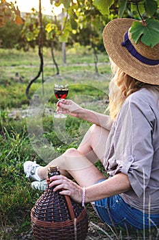 Young farmer drinking homemade red wine in vineyard