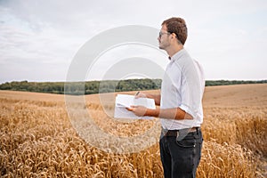 young farmer engineer standing on wheat field