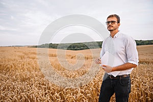 young farmer engineer standing on wheat field.