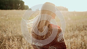 Young farmer girl walking through wheat field at sunset. Modern farming, happy youth and profession concept. Organic