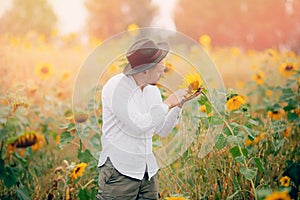 Young farmer man in hat inspects sunflowers field. Sunlight concept industrial