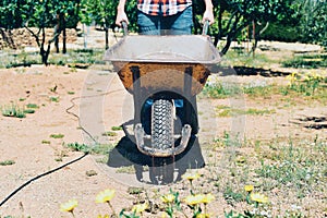 Young farmer man pushing a wheelbarrow