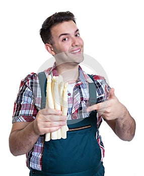 Young farmer pointing to white asparagus