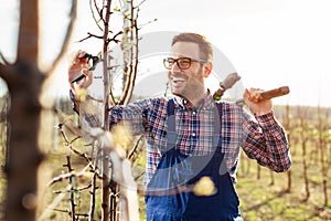 Young farmer pruning fruit tree. Agricultural occupation. Gardening at spring