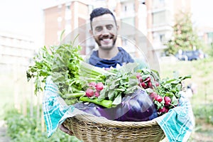 Young farmer showing a basket of vegetables in his garden