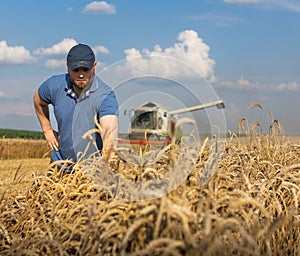 Young farmer standing on wheat field during harvest