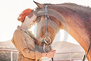 Young farmer woman hugging her horse - Cowgirl having fun inside equestrian corral ranch - Concept about love between people and photo