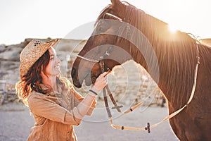 Young farmer woman playing with her bitless horse in a sunny day inside corral ranch - Concept about love between people and