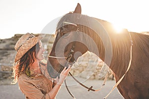 Young farmer woman playing with her bitless horse in a sunny day inside corral ranch - Concept about love between people and