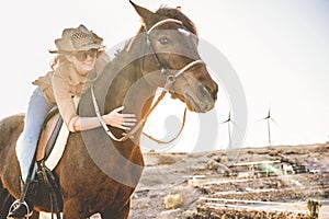 Young farmer woman riding her horse in a sunny day outdoor - Concept about love between people and animals - Focus on girl face