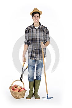 Young farmer with work tools and basket with vegetables and fruit