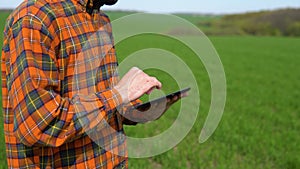 Young farmer working in a wheat field, inspecting and tuning irrigation center pivot sprinkler system on tablet