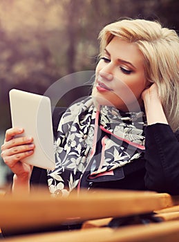 Young fashion blond business woman using digital tablet computer on bench