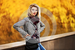 Young fashion blond woman in autumn city park