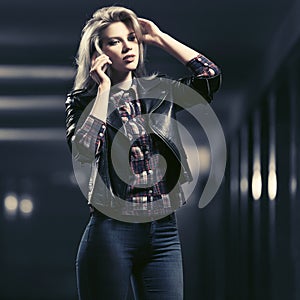 Young fashion blond woman in leather jacket calling on cell phone