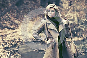 Young fashion blond woman walking in autumn forest