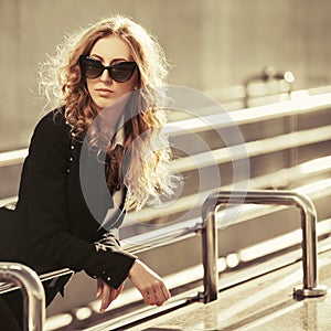 Young fashion blonde business woman in sunglasses leaning on railing