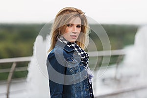 Young fashion blonde woman in denim jacket and silk scarf
