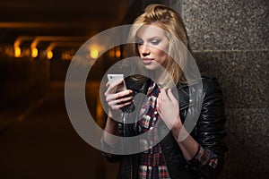 Young fashion blonde woman in leather jacket calling on cell phone