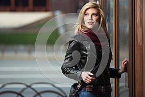 Young fashion blonde woman in leather jacket and snood scarf