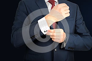 Young fashion buisness man in a blue/navy suit touching at his cufflinks