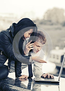 Young fashion business couple using laptop outdoor