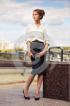 Young fashion business woman with handbag in city street