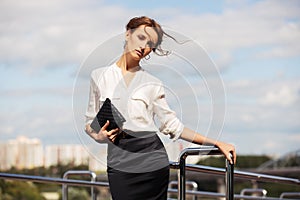 Young fashion business woman with handbag in city street