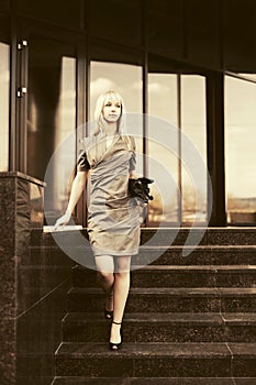 Young fashion business woman with handbag on the steps at office building