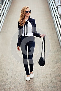 Young fashion business woman in sunglasses on the city street