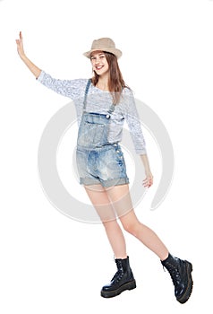 Young fashion girl in jeans overalls pushing something isolated