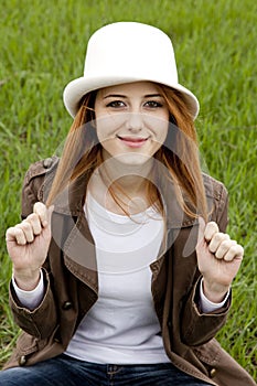 Young fashion girl in whte hat at green grass.